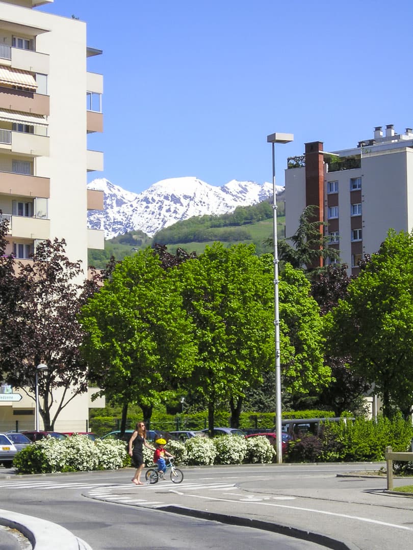 Mother and child crossing the street at Saint-Martin-d’Hères with the snow-capped Alps in background