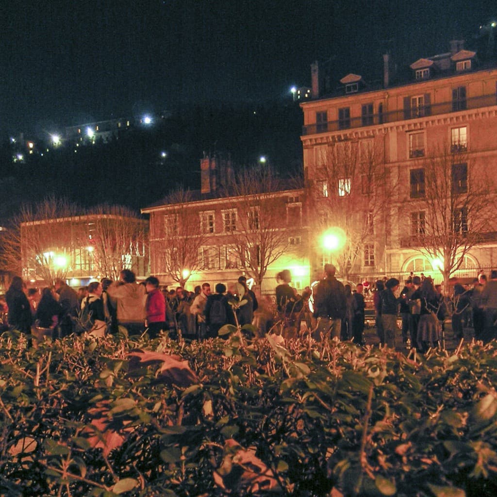 People socializing and drinking by night at the “Jardin de Ville” in Grenoble, France