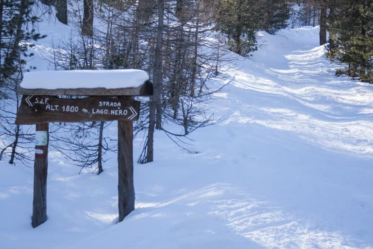 The snow-covered road to the Black Lake and the sign with snow hat